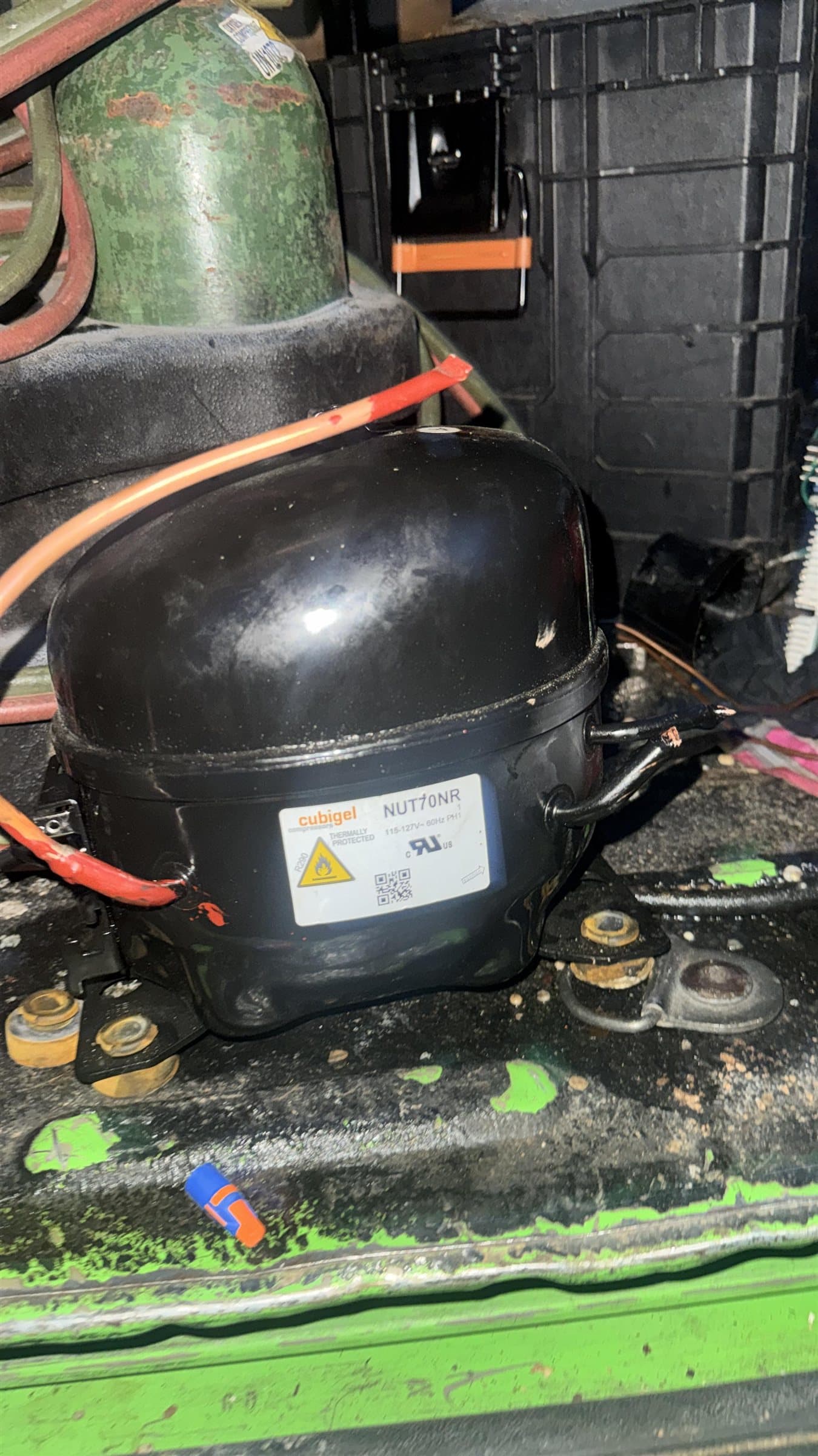 Cubigel refrigeration compressor mounted in the base of a commercial refrigeration unit.